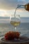 Waiter pouring aperitif white wine in glasses on outdoor tessace witn sea view