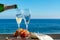 Waiter pouring Champagne, prosecco or cava in two glasses on outside terrace with sea view