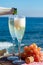 Waiter pouring Champagne, prosecco or cava in two glasses on outside terrace with sea view