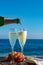 Waiter pouring Champagne, prosecco or cava in two glasses on outside terrace with sea view