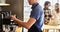 Waiter preparing coffee while couple using laptop