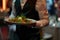 Waiter presenting gourmet salad with mozzarella and fresh vegetables