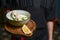 Waiter serves Okroshka in a restaurant. Summer light cold yogurt soup with cucumber, radish, eggs and dill on a board