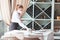 The waiter serves a table in a cafe in a protective mask