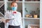 The waiter serves a table in a cafe in a protective mask