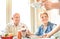 Waiter serving senior retired couple eating cakes at fashion bar