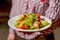 Waiter serving vegetable salad with juicy tomatoes, lettuce, radish, cucumber. Restaurant service.