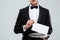 Waiter in tuxedo with bowtie holding blank card on tray