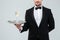 Waiter in tuxedo holding tray with glass of champagne