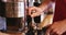 Waiter using a tamper to press ground coffee into a portafilter