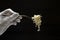 Waiter wearing white gloves holding silver fork and fresh cooked noodles on it, black background