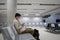 Waiting for flight at empty airport in Cyprus. Man sitting on chair with social distance marker at empty Paphos terminal