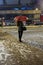 Waiting young woman with umbrella in the evening under falling snow