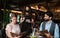 Waitress with face mask serving happy couple indoors in restaurant.