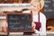 Waitress Holding Slate With Offer Written On It At Bakery