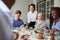 Waitress Pouring Wine For Group Of Friends Enjoying Meal In Restaurant Together