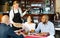 Waitress in protective mask bringing ordered pizza to guests