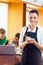 Waitress writing an order with students using laptop at coffee shop