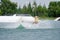 Wake boarding rider jumping trick with water splash in wake park and drone.