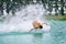 Wake boarding rider sliding and jumping trick with water splash.