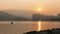 Wakeboard boat, mountain, building at sunset