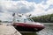 A wakeboard boat at a wooden dock in the Muskokas on a sunny day.