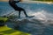 Wakeboarder cutting water with edge of board creating splashes while starting off dock