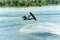 Wakeboarder jumps from a springboard behind a rope and makes a wave on the water