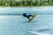 Wakeboarder jumps from a springboard behind a rope and makes a wave on the water