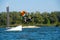 Wakeboarder, in orange shirt and helmet, is jumping