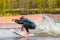 Wakeboarder on wakeboard landed in water surrounded by splash. Wakeboarding is an extreme sport