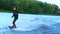 Wakeboarder waterskiing on river behind boat. Wake boarding rider
