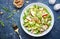 Waldorf salad with green and red apple, celery, lettuce, chicken fillet, arugula and crunchy walnuts on plate, blue table