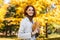 Walk and active lifestyle. Happy caucasian millennial redhead woman in raincoat hold yellow leaves