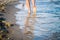 Walk along the sea shore. Surf, sand and human feet on the sea water. Selective focus