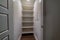 Walk in closet or pantry with empty wall shelves seen through open hinged door