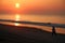 Walker on the beach at sunrise