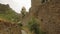 Walking by characteristic alleyway in Liguria. Handmade stone wall on the both side and church. In background green