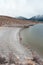 Walking the Crowley Lake beach by the columns with a red umbrealla