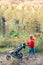 Walking mother with stroller enjoying motherhood at autumn sunset