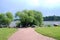 A walking path leads to small Willow trees and huge boulders on the shore of the reservoir. Summer landscape.