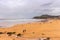 Walking people on wide beach of Biscayne bay, Spain. Surf beach with surfers and mountain on background. Active lifestyle concept.