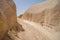 Walking unpaved rough sand trail route through desert mountain landscape of dried ancient red valley with clear sky background