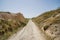 Walking unpaved rough sand trail route through landscape of dried ancient red valley with clear sky background, Cappadocia