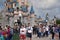 Walking visitors in theme park in front of a cute princess castle at cloudy but sunny day. Paris France, 29. May 2019