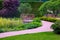 Walking walkway paved with stone tiles in park with plants and decorative bridge.