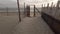 Walking in the wind at sunset   towards the sea in a fenced and sandy path