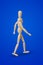 Walking wooden toy figure on blue