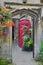 Walkway through arched doorway, flowers, phone booth, inside Magdalen College, Oxford