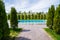 a walkway lined with tiles to the pool between the trees.